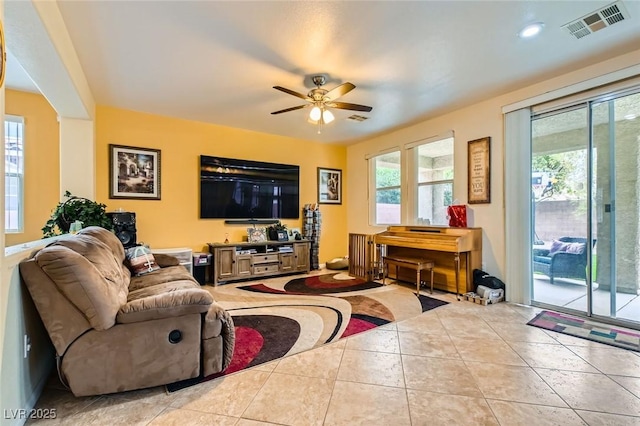 tiled living area with a wealth of natural light, visible vents, and ceiling fan