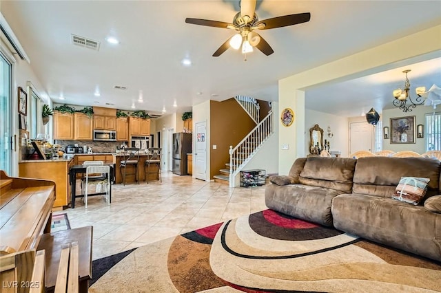 living room with visible vents, ceiling fan with notable chandelier, recessed lighting, stairway, and light tile patterned floors