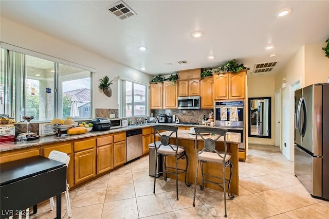 kitchen featuring light stone countertops, visible vents, backsplash, and stainless steel appliances