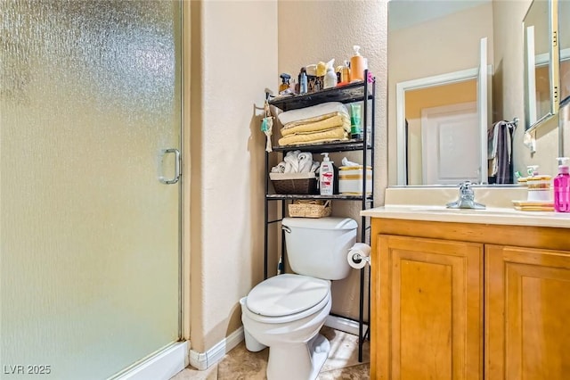 bathroom with vanity, a shower stall, toilet, and baseboards