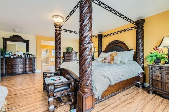 bedroom with wood finished floors, visible vents, and baseboards