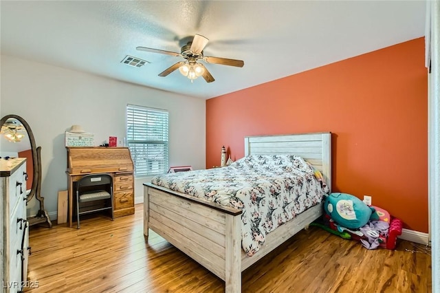 bedroom featuring light wood-type flooring, baseboards, visible vents, and a ceiling fan