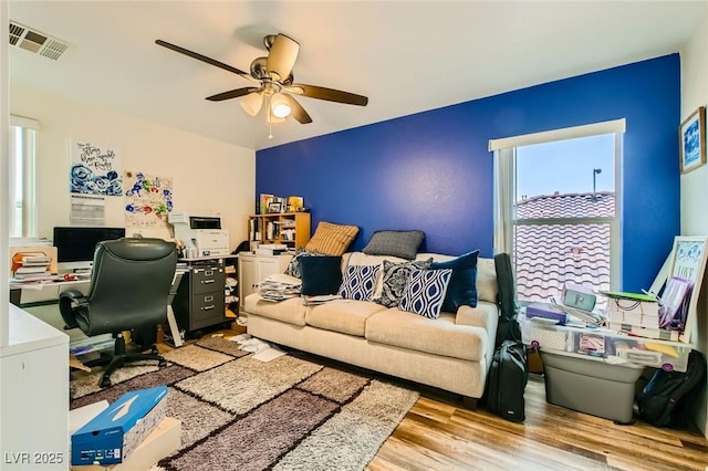 home office with visible vents, light wood-style floors, and ceiling fan