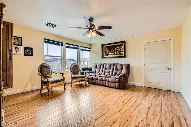 living room featuring visible vents, baseboards, light wood-style floors, and ceiling fan