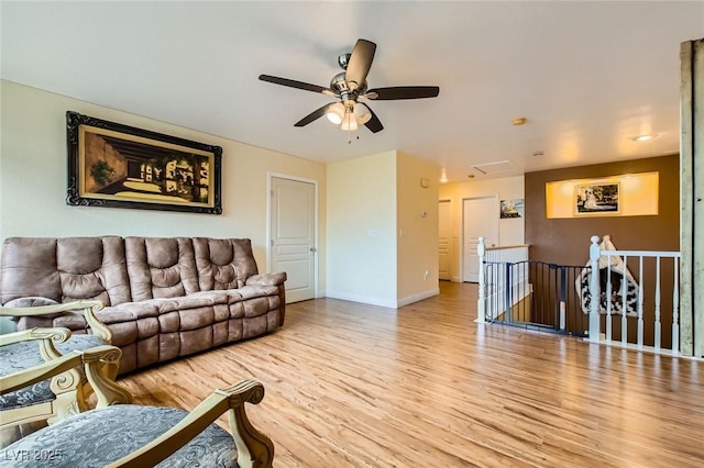 living area with baseboards, wood finished floors, and ceiling fan