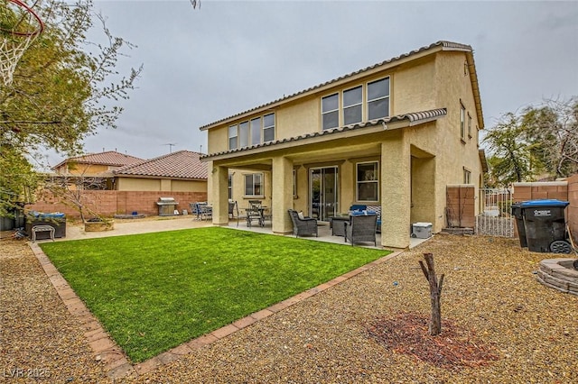 rear view of house featuring fence, stucco siding, a lawn, a patio area, and a gate