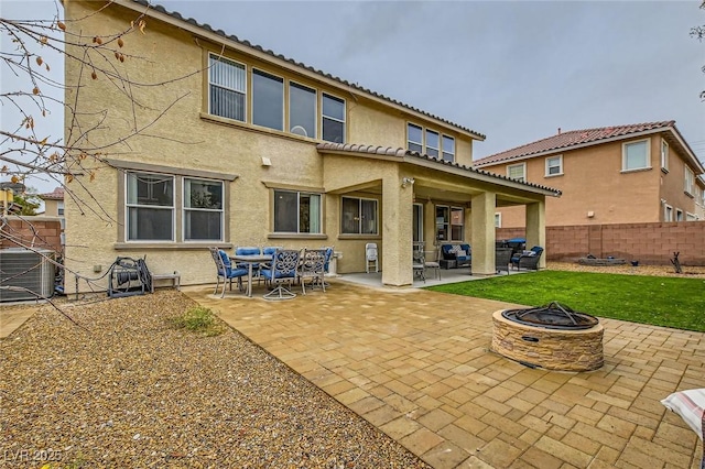 back of house with an outdoor living space with a fire pit, a patio, fence, and stucco siding