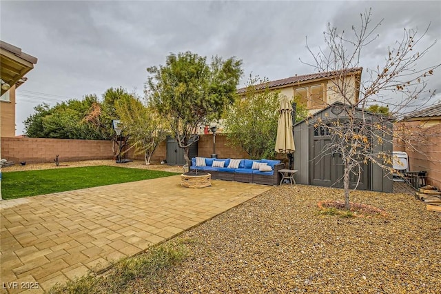 view of yard with an outdoor living space with a fire pit, a fenced backyard, a shed, and a patio area