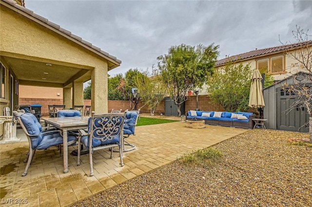 view of patio / terrace featuring outdoor dining space, an outdoor living space, a fenced backyard, an outdoor structure, and a storage shed