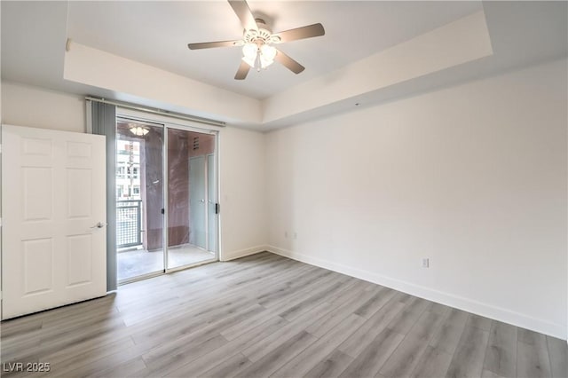 unfurnished bedroom with a raised ceiling, access to exterior, and light wood finished floors