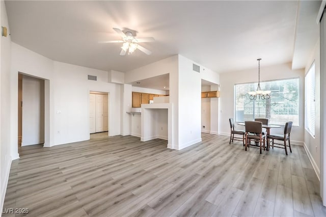 interior space with visible vents, baseboards, light wood-style flooring, and ceiling fan with notable chandelier