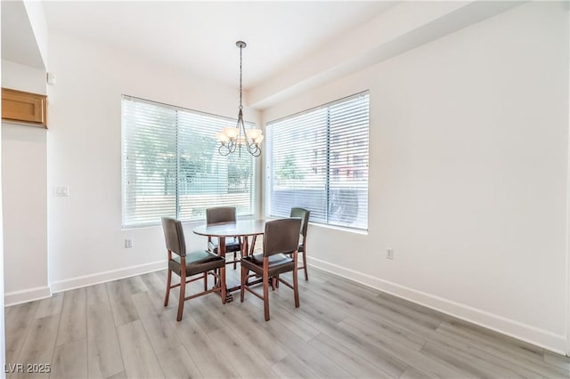 dining room with light wood-type flooring, baseboards, and a notable chandelier