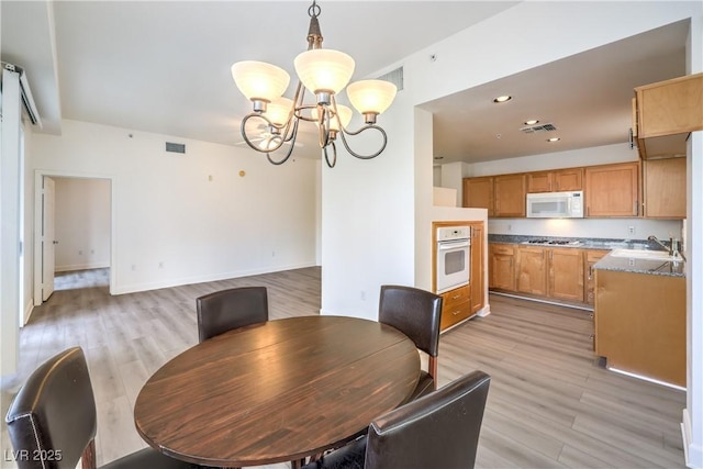 dining room featuring a chandelier, visible vents, and light wood-type flooring