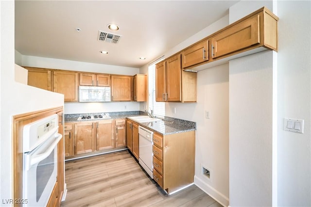 kitchen featuring a sink, white appliances, visible vents, and light wood-type flooring