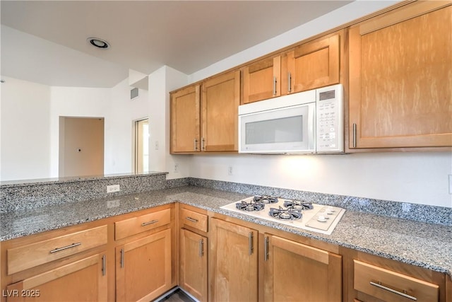 kitchen featuring light stone counters, visible vents, brown cabinets, and white appliances