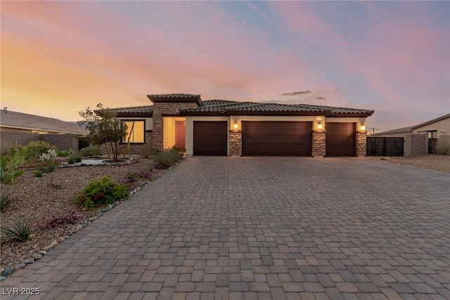 view of front of home featuring stucco siding, a garage, stone siding, a tiled roof, and decorative driveway