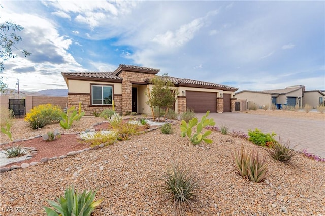 view of front of home with driveway, stucco siding, a garage, stone siding, and a tiled roof