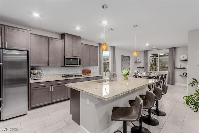 kitchen with tasteful backsplash, dark brown cabinets, appliances with stainless steel finishes, and a sink