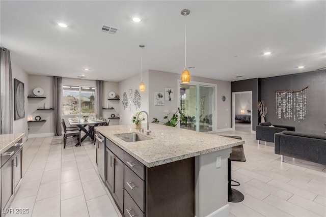 kitchen featuring light stone counters, visible vents, a sink, dark brown cabinetry, and dishwasher