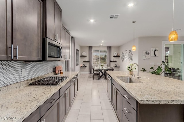 kitchen with visible vents, dark brown cabinets, decorative backsplash, stainless steel appliances, and a sink