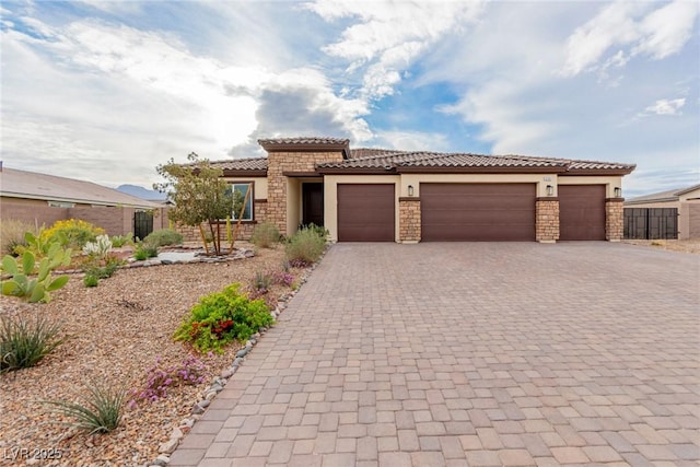 mediterranean / spanish home with a tiled roof, decorative driveway, fence, and a garage