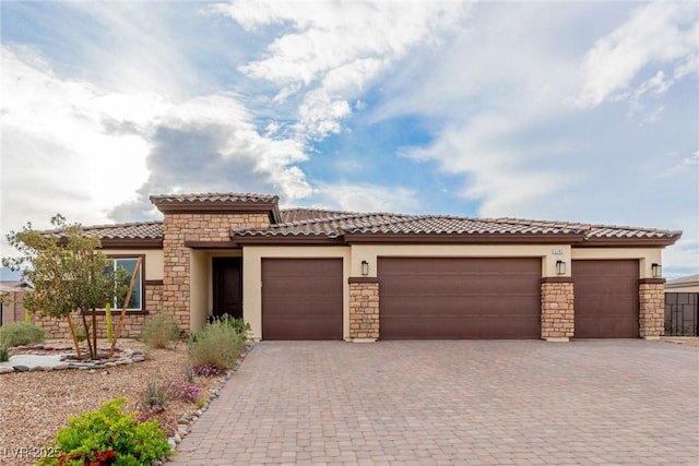 mediterranean / spanish-style home featuring a tile roof, decorative driveway, an attached garage, and stucco siding