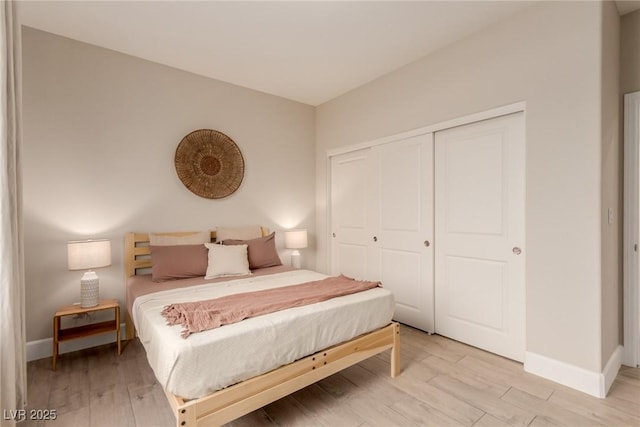 bedroom featuring a closet, light wood-style flooring, and baseboards