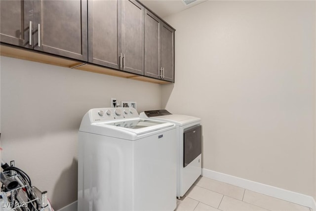 washroom featuring cabinet space, light tile patterned floors, washing machine and dryer, and baseboards