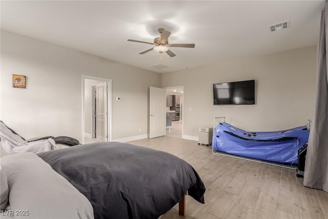 bedroom featuring baseboards, visible vents, light wood finished floors, and ceiling fan