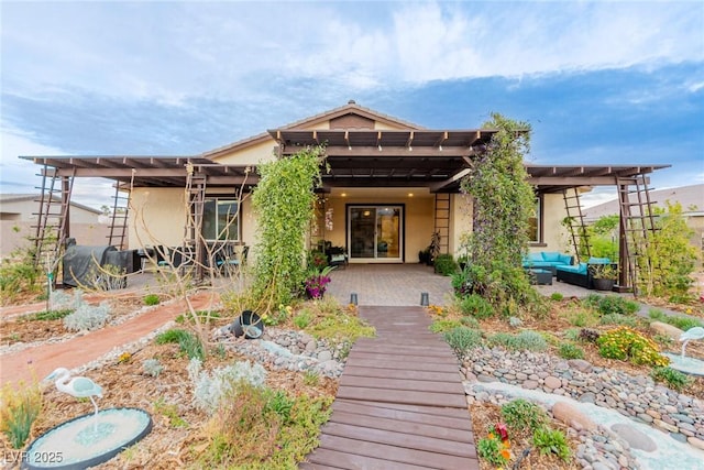 back of property with stucco siding, an outdoor hangout area, and a pergola