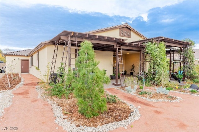 exterior space with stucco siding, a patio area, and a pergola