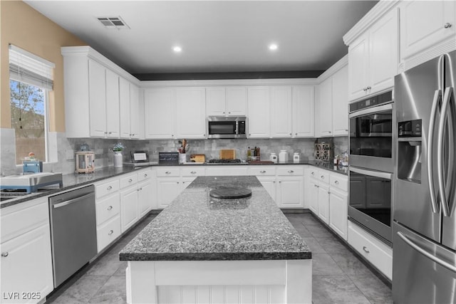 kitchen featuring visible vents, backsplash, appliances with stainless steel finishes, and white cabinetry