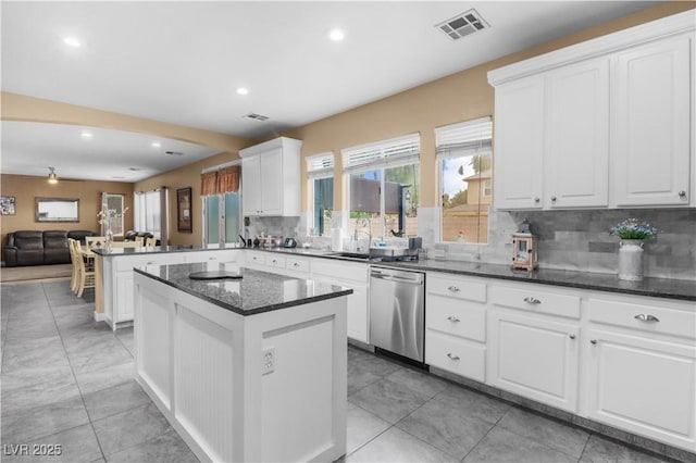 kitchen with stainless steel dishwasher, a peninsula, visible vents, and a wealth of natural light