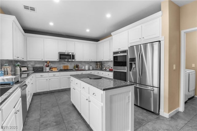 kitchen with visible vents, independent washer and dryer, a kitchen island, appliances with stainless steel finishes, and white cabinets