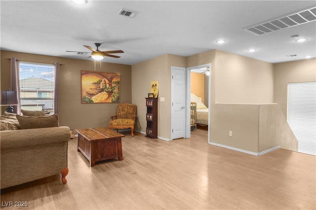 living room with ceiling fan, visible vents, and light wood-type flooring