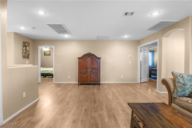 living area with visible vents, arched walkways, and light wood finished floors