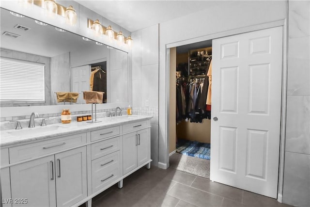 bathroom featuring tile patterned floors, visible vents, double vanity, and a sink