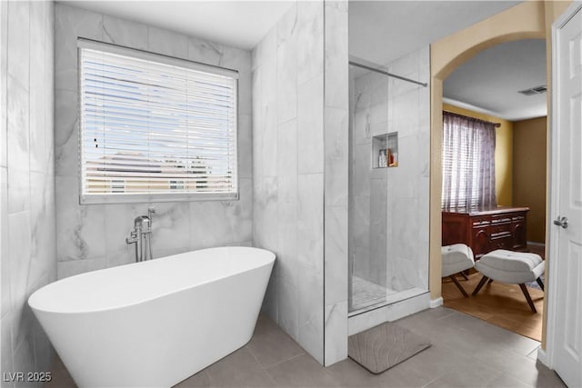 bathroom with a shower stall, a freestanding tub, a healthy amount of sunlight, and visible vents