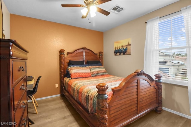 bedroom with a ceiling fan, light wood-style floors, visible vents, and baseboards