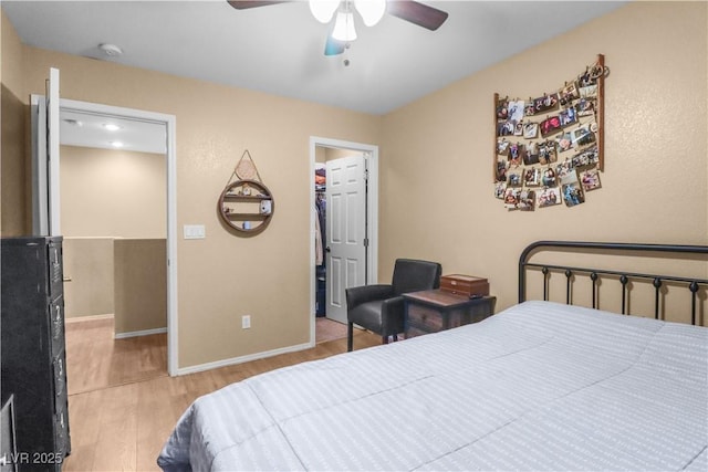 bedroom featuring a ceiling fan, a spacious closet, wood finished floors, and baseboards