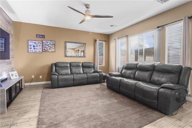 living area with visible vents, ceiling fan, baseboards, and light wood-style floors