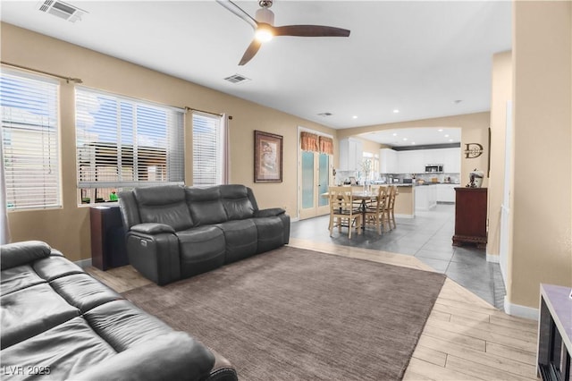 living room featuring a wealth of natural light, visible vents, and a ceiling fan