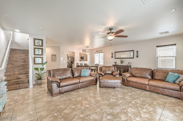 living area featuring visible vents, stairs, and ceiling fan