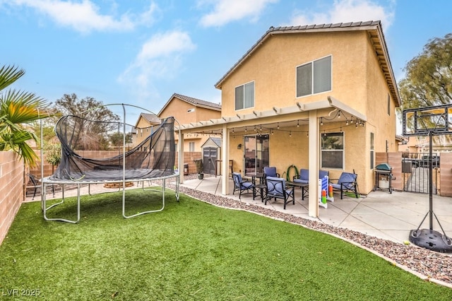 back of property featuring a patio area, a trampoline, a fenced backyard, and stucco siding