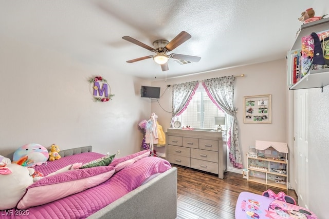 bedroom featuring a ceiling fan, wood finished floors, visible vents, and a textured ceiling