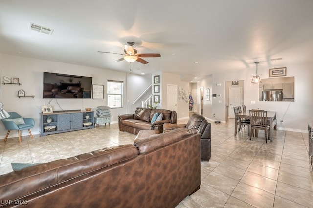 living room with visible vents, light tile patterned flooring, ceiling fan, and stairs