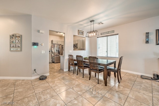 dining space featuring light tile patterned floors, visible vents, and baseboards