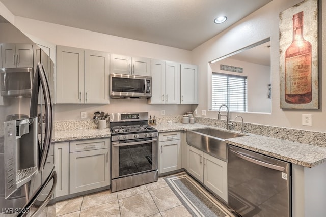 kitchen featuring a sink, stainless steel appliances, light stone counters, and light tile patterned floors