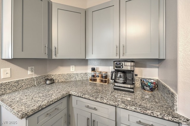 kitchen with gray cabinets, a textured wall, and light stone countertops