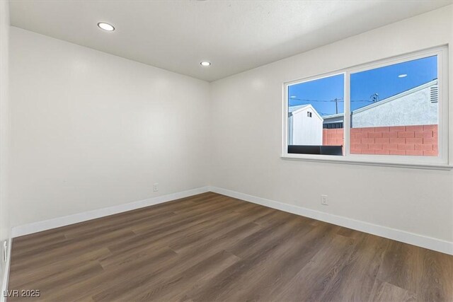 empty room with dark wood finished floors, recessed lighting, and baseboards